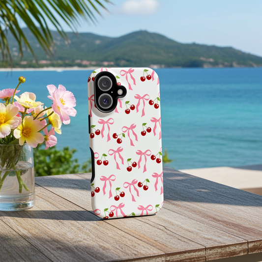 iPhone case with cherry and bow pattern on a wooden table with a scenic background